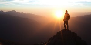 Person at mountain peak during sunrise